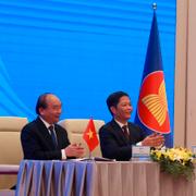 Vietnams premiärminister Nguyen Xuan Phuc och handelsminister Tran Tuan Anh, bredvid en skärm som visar Kinas premiärminister Li Keqiang och handelsminister Zhong Shan hålla upp RCEP-avtalet. 