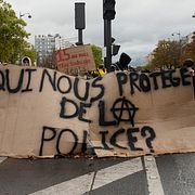 Elever står bakom ett plakat med orden ”Vem skyddar oss från polisen?”.