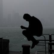 En man sitter i Victoria Harbour i Hong Kong i väntan på stormen