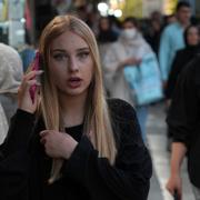 En ung kvinna utan den obligatoriska slöjan talar i telefon i ett shoppingområde i Teheran, 2023.