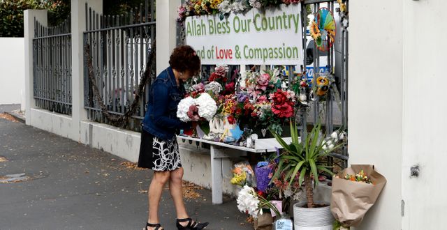Kvinna lägger blommor vid en minnesplats ett år efter attacken den 15 mars. Mark Baker / TT NYHETSBYRÅN