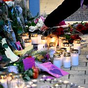 Människor tänder ljus och lämnar blommor vid Kämpetorpshallarna i Solberga i södra Stockholm där en kvinna sköts till döds i fredags.