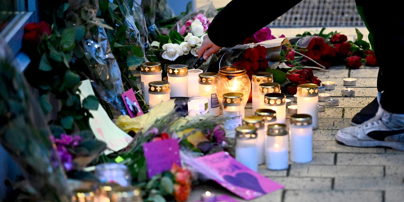 Människor tänder ljus och lämnar blommor vid Kämpetorpshallarna i Solberga i södra Stockholm där en kvinna sköts till döds i fredags.