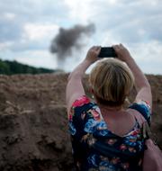 En journalister fotar röken från en exploderande landmina. Natacha Pisarenko / AP