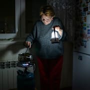 En kvinna i Kyiv lagar mat under ett strömavbrott.