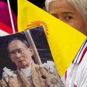 Kvinna håller upp porträtt av kung Bhumibol. Arkiv.