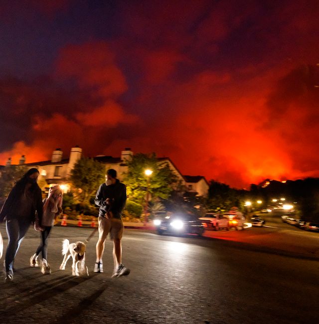 Residents walk a dog as a brush fire burns behind homes in the Pacific Palisades area of Los Angeles on Saturday, May 15, 2021. Ringo H.W. Chiu / TT NYHETSBYRÅN