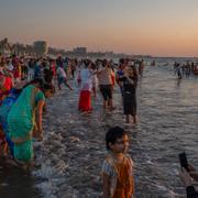 Människor tar bilder när solen går ner i Arabiska havet vid den indiska staden Bombay.