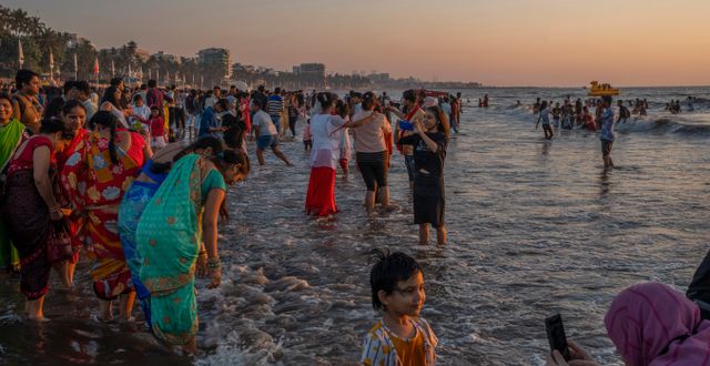 Människor tar bilder när solen går ner i Arabiska havet vid den indiska staden Bombay. Rafiq Maqbool / AP