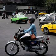 En korsning i centrala Teheran, med en antiamerikansk propagandaskylt i bakgrunden.