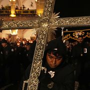 En man håller ett kors under en procession i Antigua i Guatemala på långfredagen