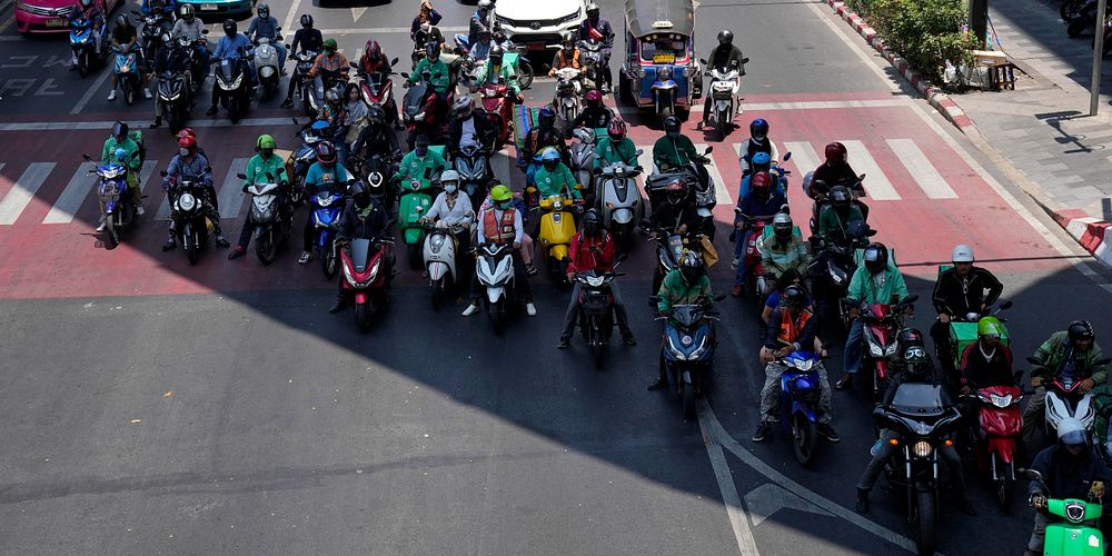 Motorcyclists stop in the shade of a skytrain line on a hot day in Bangkok, Thailand, Friday, May 3, 2024. (AP Photo/Sakchai Lalit)  XYA114