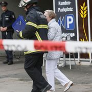 En polis hjälper en äldre kvinna efter knivdådet på fredagen.