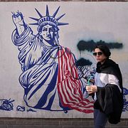 En kvinna vid en mur med antiamerikanska budskap i Teheran.