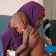 En oidentifierad mamma bär sin undernärde son i Somalia. 