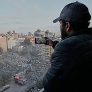 En man filmar med sin mobil medan räddningsarbetare söker genom rasmassorna efter en israelisk flygattack i centrala Beirut den 18 mars 2026.