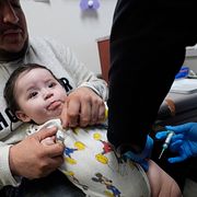 Cesar Acevedo håller sin son Adriel Acevedo medan sjuksköterskan Tracey McElroy ger honom poliovaccin på en klinik i Dallas den 4 april 2025.