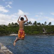 En pojke hoppar i vattnet i Alofi, Niue.