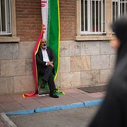 Man lutar sig mot en iransk flagga under en manifestation som stöttas av regimen. Arkivbild från Teheran.
