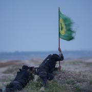 En shiamilis som strider mot IS placerar en flagga i marken utanför irakiska Tikrit.