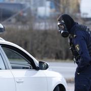 Polis i gasmask som stoppar bilist utanför Säpos högkvarter i Solna.