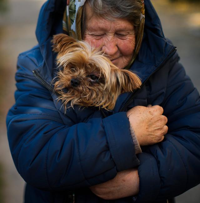 A woman warms her dog in Kivsharivka, Ukraine, Sunday, Oct. 16, 2022. As temperatures drop below freezing in eastern Ukraine, those who haven't fled from the heavy fighting, regular shelling and months of Russian occupation are now on the threshold of a brutal winter and digging in for the cold months. Francisco Seco / AP