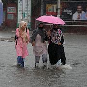 Personer går över en översvämmad gata i Jammu i Indien. 