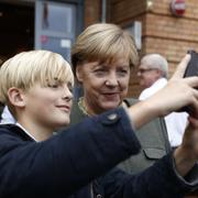 Angela Merkel valkampanjar och tar en selfie ihop med en pojke.