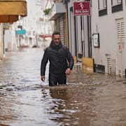En man vadar på en gata i översvämmade Alcácer do Sal i södra Portugal.