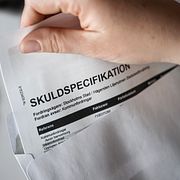 Anonym person med miniräknare, räkningar, skulder.