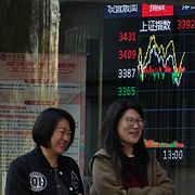 Kvinnor passerar en skärm som visar Shanghaibörsens index utanför en mäklarfirma i Peking. Arkivbild.