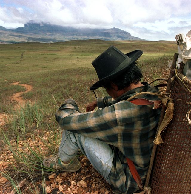 File photo: Pemon Indian Lucio Ayuso rests as he carries food in a handmade backpack as he works as a porter for tourists hiking to Rormaima tepuy, in distance at right, and Kukenan tepuy, in distance at left, in Canaima National Park in Venezuelas Gran Sabana region, Jan. 7, 2004. LESLIE MAZOCH / Ap