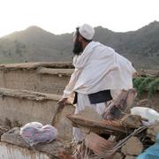 En man vid en förstört hus i byn Gayan, Afghanistan