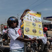 En taxichaufför på motorcykel visar upp ett informationsblad om ebola.