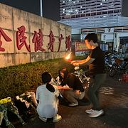 Folk placerar blommor och tänder ljus utanför idrottsanläggning i Zhuhai för att hedra offren.