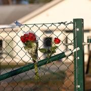 Blommor på stängslet utanför det vårdboende i Enköping där en ung kvinna i personalen dödades.