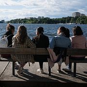 En grupp unga tjejer sitter på en bänk vid Hornsbergs strand och njuter av solen.