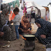 Siham Omran, 54, lagar mat intill sitt tält i Khan Yunis.