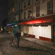 En ensam man leder sin cykel utanför en stängd restaurang i Montmartre, Paris. 