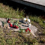 Blommor och ljus på minnesplatsen vid bryggan.