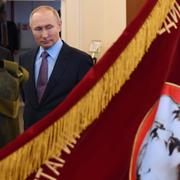 Rysslands president Vladimir Putin tittar på en banderoll från sovjettiden som föreställer Sovjetunionens grundare Vladimir Lenin och Josef Stalin.