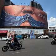 Människor kör förbi en billboard föreställande Hormuzsundet och USA:s president Donald Trump i Teheran. Illustrationsbild.