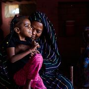 Rashiqa Alqadi håller barnbarnet Anfal Aljozoor, 11 i byn Qoz Nafisa i Sudan.