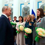 Putin delar ut blommor till kvinnor.