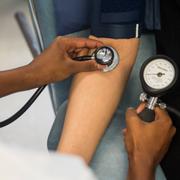 Kvinnlig läkare mäter blodtrycket på patient.