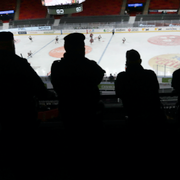 Amanda Lind och poliser som tittar på en ishockeymatch utan publik. 