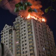 En kvinna tittar upp mot ett bostadshus som träffats av en rysk attack.