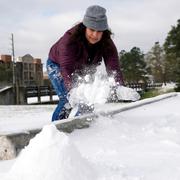 Kvinna borstar bort snö. 