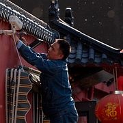 En man sätter upp en övervakningskamera utanför en restaurang i Peking.