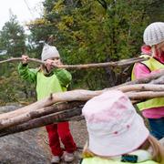 Förskolebarn leker i skogen. 